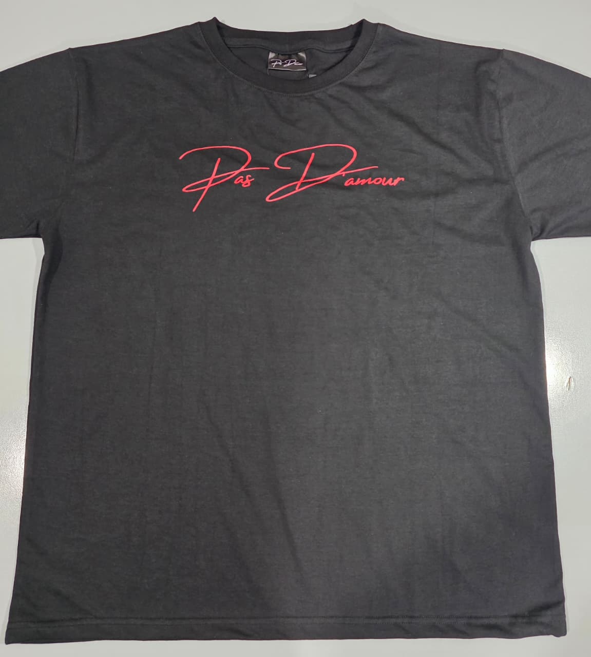Black t-shirt with red 'Pas D'amour' text on a light gray background