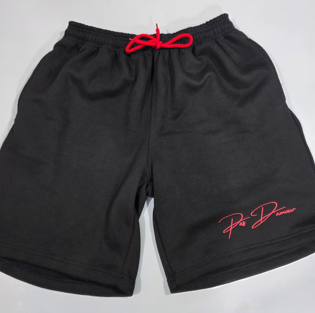 Black shorts with red drawstring and logo on a white background